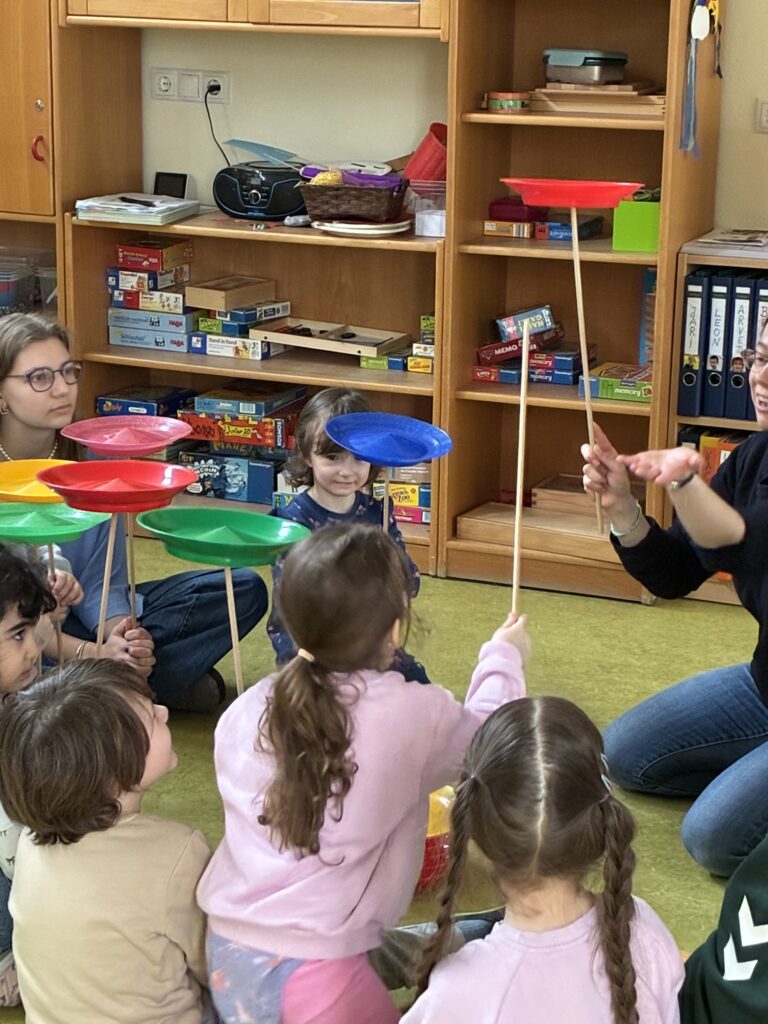 Die Kinder erproben das Jonglieren mit Tellern auf einem Stab.