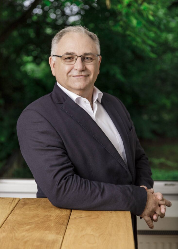 Jörg Angerstein, Vorstand der Hans Wendt Stiftung - steht freundlich lächelnd an einen Tisch gelehnt