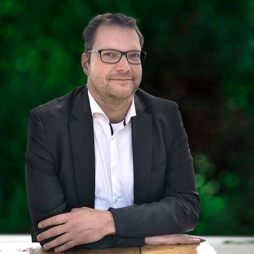 Volker Wehmann, Bereichsleitung Finanzen der Hans-Wendt-Stiftung, mit freundlichem Gesicht an einem Tisch lehnend