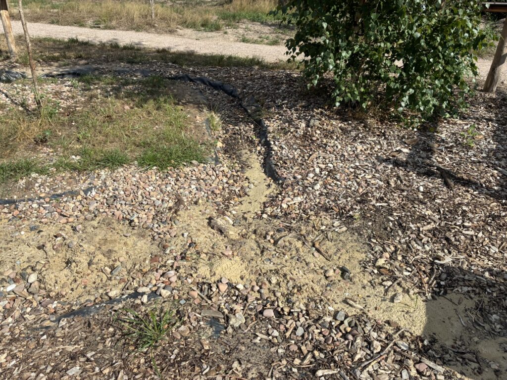 Wasserlauf aus Kies, der zugeschüttet ist mit Sand, auf dem Wasserspielplatz der Kinder- und Jugendfarm