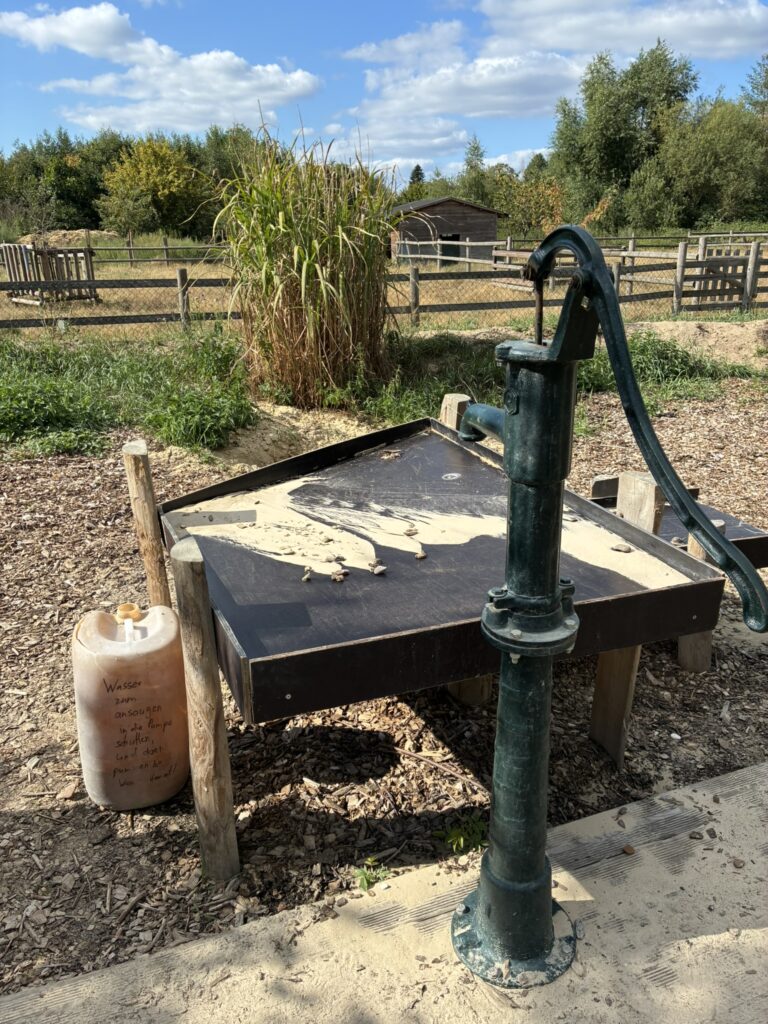Wasserpumpe mit an einer Seite abgesenktem Wassertisch auf dem Wasserspielplatz der Kinder- und Jugendfarm